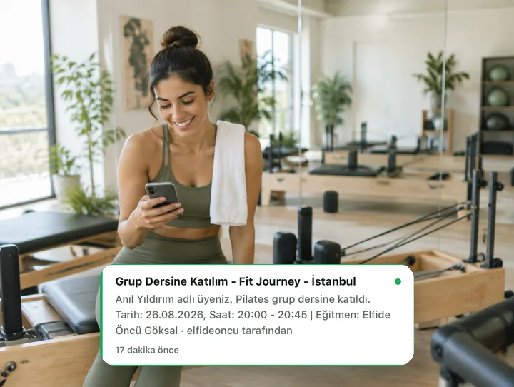 Reformer üzerinde telefonundan Fitjourney ders bildirimine bakan üye